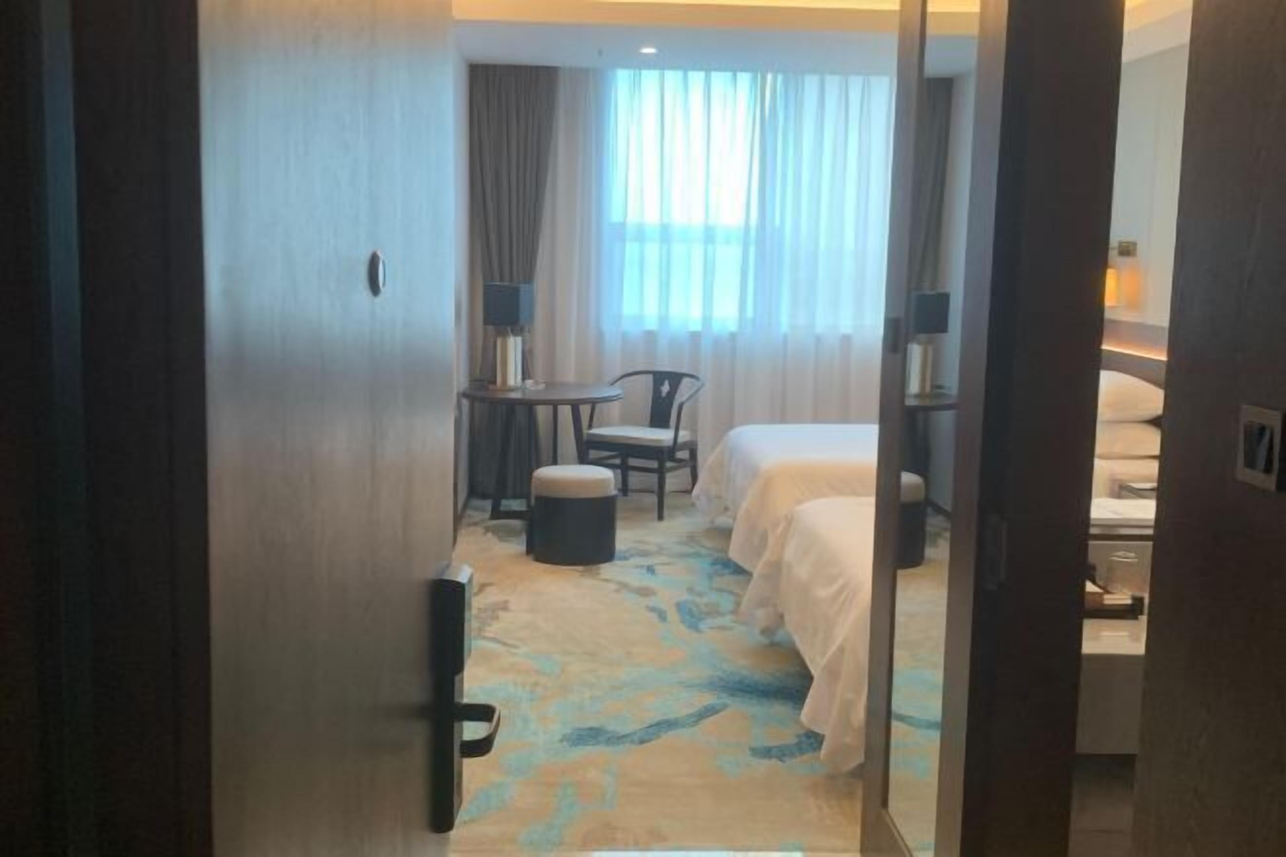 Una habitación de hotel con cama, escritorio, silla y una mesita.