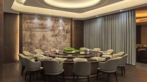 A modern dining area with a round table, multiple chairs, and a decorative wall. - Jincheng Hotel (Linqu)