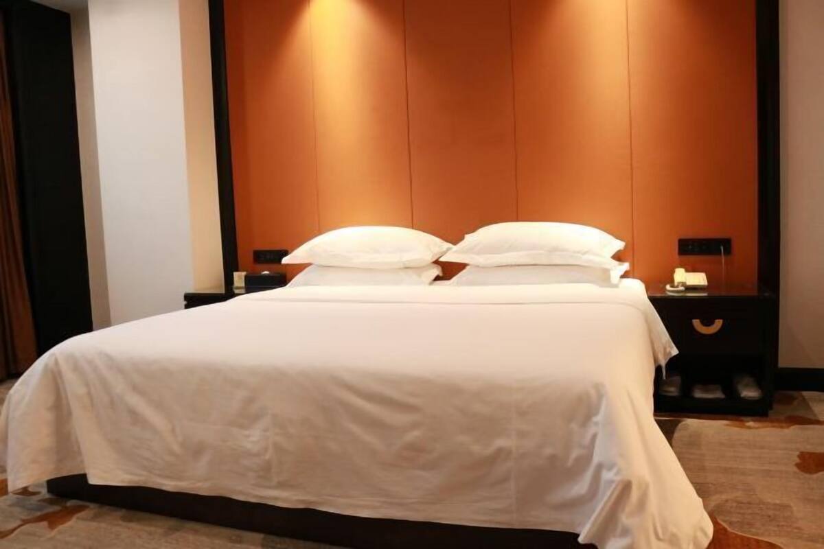 Une chambre d’hôtel avec un grand lit, deux tables de chevet et une tête de lit en bois.
