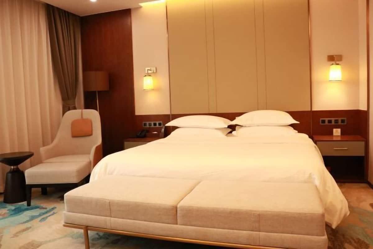 Une chambre d’hôtel avec un lit, une chaise, une table de chevet et une lampe.