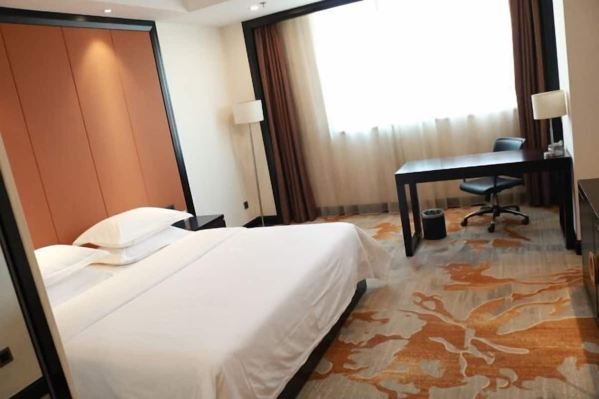 Une chambre d’hôtel avec un lit, un bureau, une chaise et une lampe.