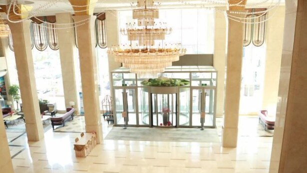 A spacious lobby with a large chandelier, a glass partition, and a reception desk. - Jincheng Hotel (Linqu)