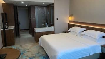 Ein Hotelzimmer mit einem großen Bett, einem Nachttisch, einem Spiegel, einer Duschkabine und einem kleinen runden Tisch.