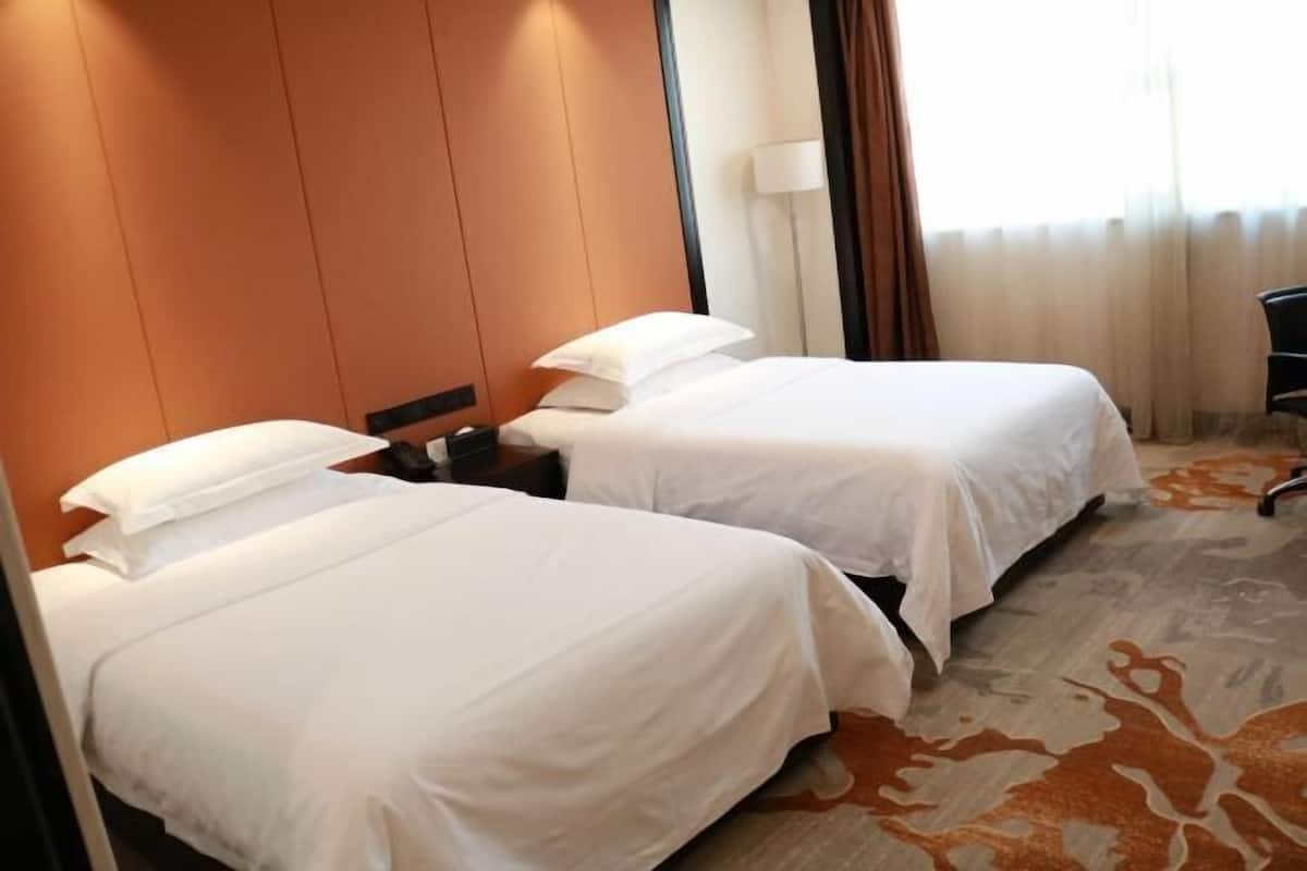 Une chambre d’hôtel avec deux lits, une table de chevet, une lampe et une chaise.