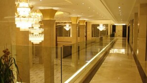 A long, well-lit corridor with chandeliers and glass railings, leading to a room with patterned curtains. - Jincheng Hotel (Linqu)
