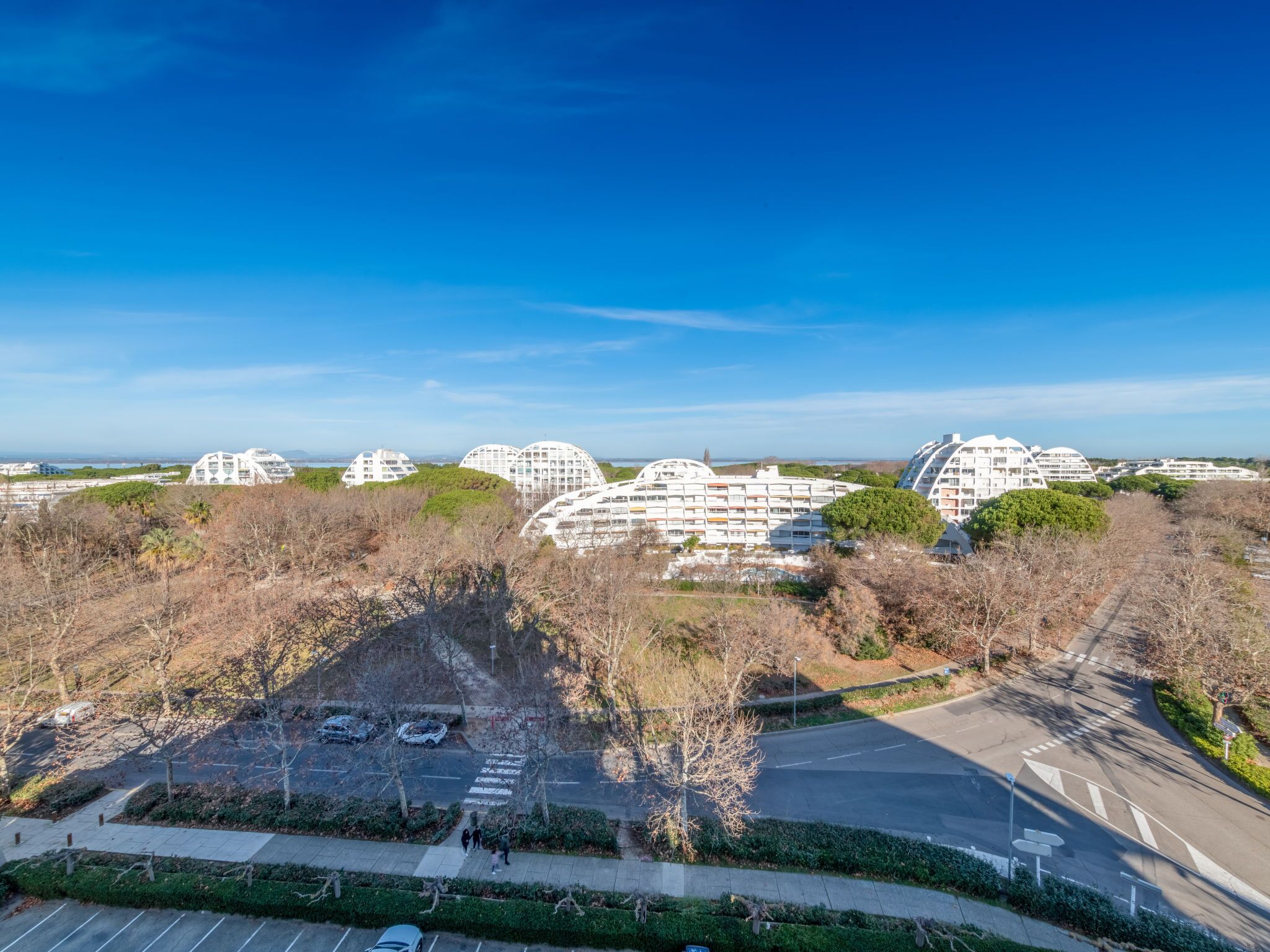 A modern residential area with unique dome-shaped buildings, a parking lot, and a clear blue sky.