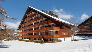 Un immeuble à plusieurs étages doté de balcons, entouré de neige.