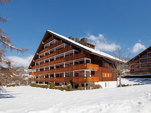 A multi-story building with balconies, surrounded by snow.