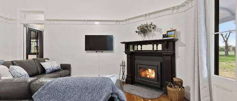 Un salon avec une cheminée, un canapé, un téléviseur et une vue par la fenêtre.