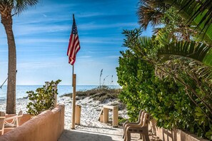 Uitzicht op het strand met een Amerikaanse vlag, palmbomen en zand.