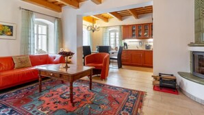 A spacious living room with a red sofa, a wooden coffee table, and a patterned rug. There is a kitchen in the background with wooden cabinets and a fireplace. - Vacation home Frilo by Interhome (Broumov)