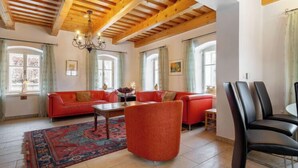 A spacious living room with a wooden ceiling, a red sofa, a coffee table, and a dining area with chairs. - Vacation home Frilo by Interhome (Broumov)