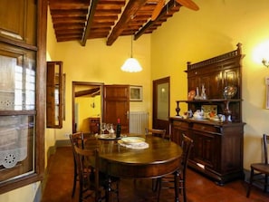 A dining area with a wooden table and chairs, a ceiling fan, and a wooden cabinet with various items on top.