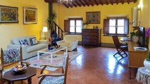 Un salon spacieux avec un canapé, des fauteuils, une table basse et une cheminée.