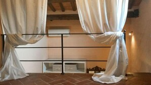 Une pièce avec un lit, un plafond en bois et une fenêtre avec des rideaux.