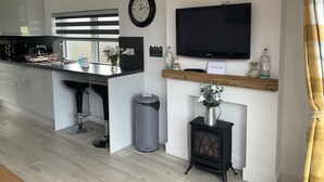 Een moderne keuken met een inbouwkookeiland, een zwart fornuis, een aan de muur bevestigde televisie en een klok.