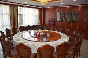 Un salón de conferencias con una mesa redonda, sillas de madera y una lámpara de araña.