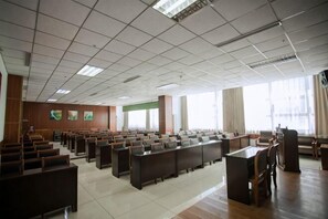 A conference room with rows of tables and chairs, large windows, and a high ceiling. - Kaiyuan Business Hotel (Zhuolu)