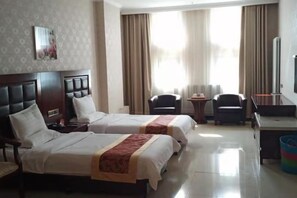 Une chambre d’hôtel avec deux lits, un bureau, une chaise, une télévision et une fenêtre avec des rideaux.