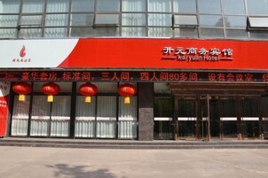 Un hotel con fachada roja y blanca, amplios ventanales de vidrio y un letrero que indica que se trata del Hotel Kaiyuan.