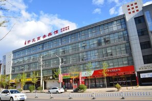 Un edificio moderno con varios pisos, grandes ventanales y un llamativo letrero rojo en la fachada.
