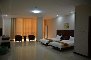 Habitación de hotel con dos camas, un escritorio, una silla y un ventanal con cortinas.