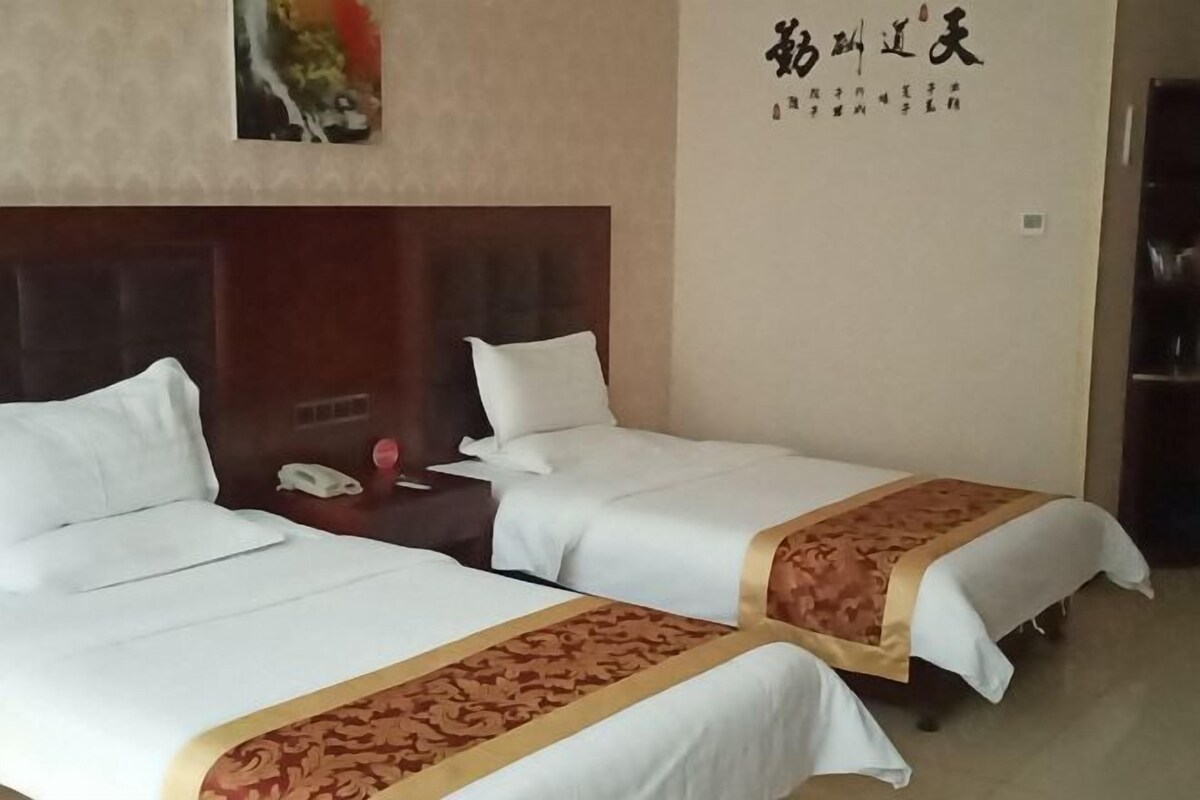 Habitación de hotel con dos camas, un cabecero de madera, un teléfono y una pared con caracteres chinos.