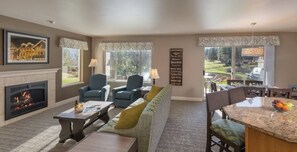 Cozy living room with a fireplace, comfortable seating, and a dining area offering a view of the outdoors.