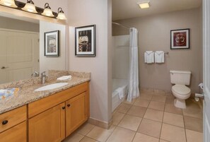 Bathroom features a granite countertop, wooden cabinets, and a shower curtain.