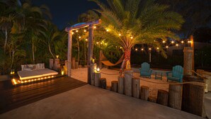 A beachside lounge area with a hammock, seating, and string lights. - MAGR LUXURY (Cutler Bay)