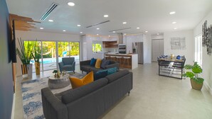 A modern living room with a grey sofa, a coffee table, and a dining area with a table and chairs. - MAGR LUXURY (Cutler Bay)