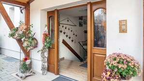 A wooden staircase leading to a room with a white wall, a wooden door, and a small indoor garden with flowers and a pine cone. - Holiday Apartment Waldruhe with Balcony, Mountain View & Wi-Fi (Garmisch-Partenkirchen)
