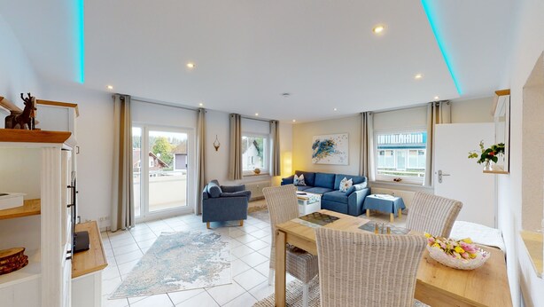 Un salon spacieux comprenant un canapé, une table à manger avec des chaises, une grande fenêtre et une vue sur l’extérieur.