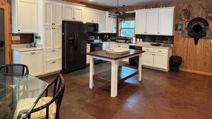 A kitchen with white cabinets, a black refrigerator, and a dining table with chairs.