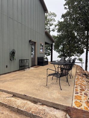 Un patio con mesa y sillas, una zona de estar cubierta y un muro de piedra.