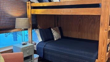 A bunk bed with a desk and chair, a window with a view, and a wooden floor.