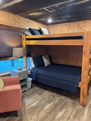 A bunk bed with a desk and chair, a window with a view, and a wooden floor.