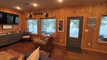 A cabin interior with wooden walls, a television, a sofa, and a sign with outdoor activities.