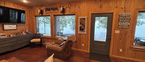 A cabin interior with wooden walls, a television, a sofa, and a sign with outdoor activities.