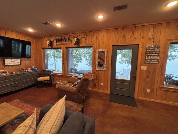 A cabin interior with wooden walls, a television, a sofa, and a sign with outdoor activities.