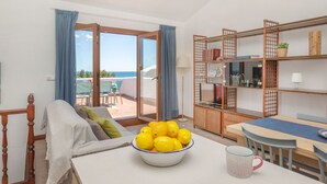 Una habitación con una cama, una mesa con un bol de limones, una taza de café y vistas al mar a través de un ventanal.