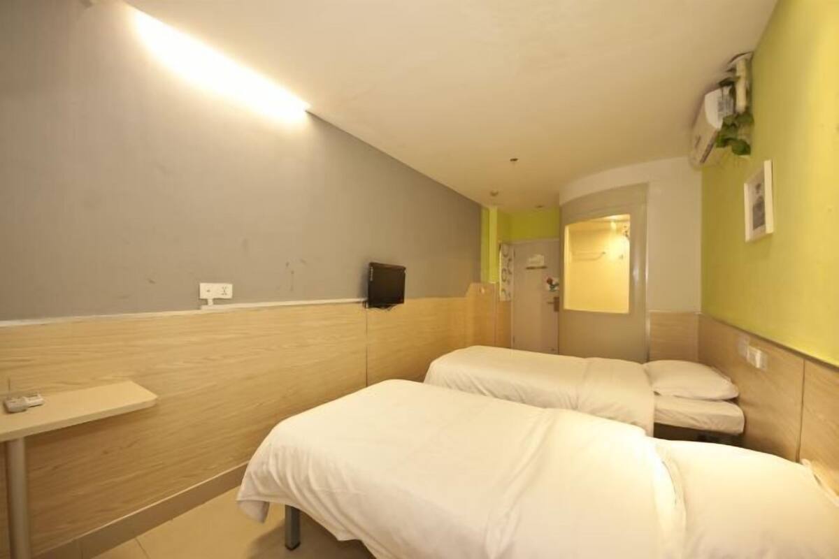 A hotel room with two beds, a small table, and a mirror.