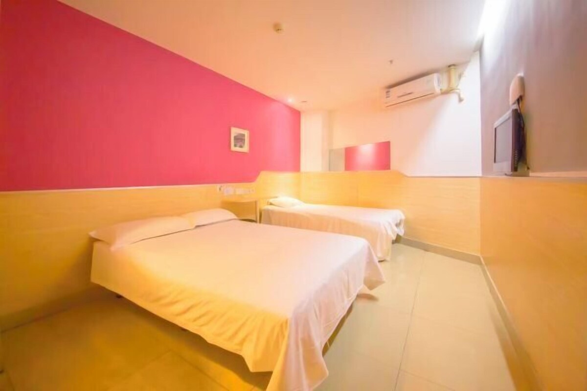 Habitación de hotel con dos camas, una pared roja y un televisor.