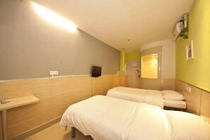 Una habitación de hotel con dos camas, un cabecero de madera, una mesita y un espejo.