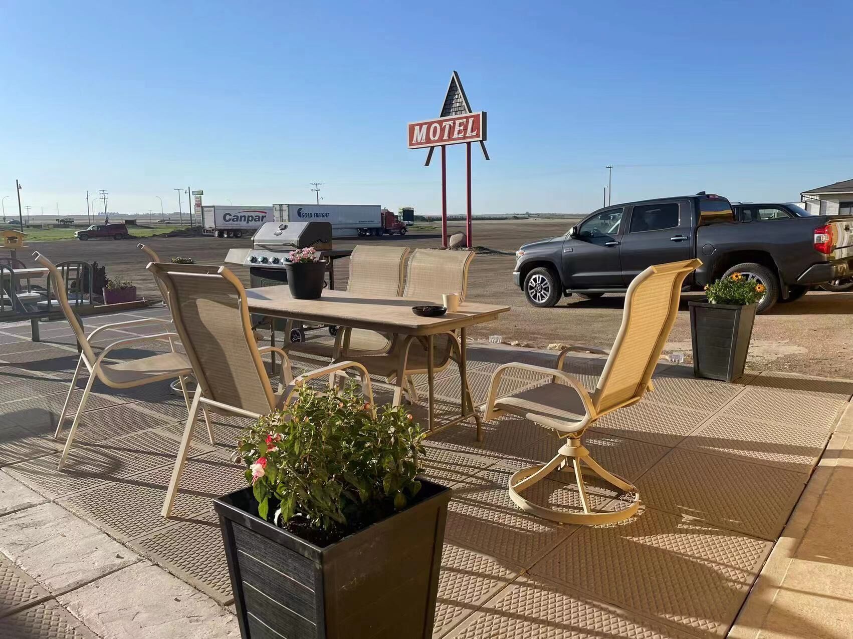 A motel with outdoor seating, a grill, and a signboard.