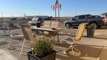 A motel with outdoor seating, a grill, and a signboard.