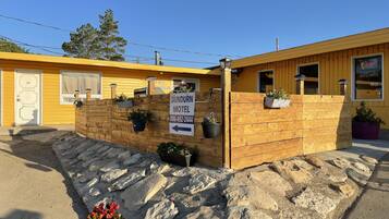 A motel with a wooden facade, a signboard, and potted plants.