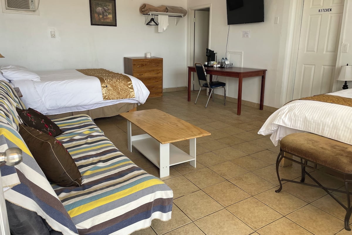 Una habitación de hotel con cama, sofá, mesita, escritorio y televisor.