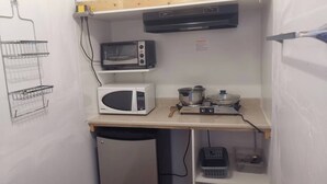 Een kleine keuken met een magnetron, fornuis en kleine koelkast.