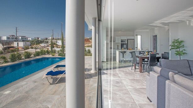 Un espacio de estar moderno con piscina, comedor y cocina.